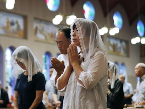 Christians pray for the victims of U.S. atomic bombing during a mass at Urakami Cathedral in Nagasaki, southern Japan, Thursday, Aug. 9, 2018, marking the 73rd anniversary of the bombing on the city.