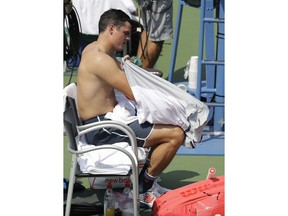 Milos Raonic, of Canada, changes his shirt during a changeover in his match against Gilles Simon, of France, during the second round of the U.S. Open tennis tournament, Wednesday, Aug. 29, 2018, in New York.