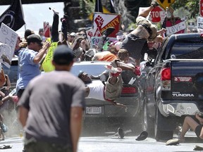FILE - In this Aug. 12, 2017, file photo, people fly into the air as a vehicle drives into a group of protesters demonstrating against a white nationalist rally in Charlottesville, Va. Efforts to take down America's monuments honoring slain Confederate soldiers and the generals who led them gained explosive momentum following the deadly violence a year ago in Charlottesville. The vehicle plowed into a crowd protesting a gathering of white supremacists whose stated goal was to protect a statue of Gen. Robert E. Lee.