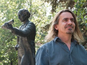 Patrick Johnson, a self-proclaimed vandal who claims responsibility for the recent red spray paint applied to the John A. Macdonald statue in Victoria Park, stands next to the statue in Regina Thursday.