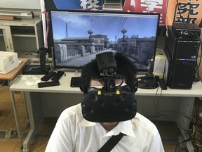 Namio Matsura, 17-year-old member of the computation skill research club at Fukuyama Technical High School, watches Hiroshima city before atomic bomb fell in virtual reality experience at the high school in Hiroshima, western Japan.
