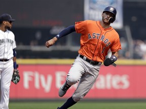 Houston Astros' Carlos Correa (1) races past Seattle Mariners third baseman Robinson Cano to score in the first inning of a baseball game Wednesday, Aug. 22, 2018, in Seattle.