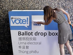 A voter places her ballot into a drop box Tuesday, Aug. 7, 2018, in Seattle. Washington voters will decide which candidates advance to the November ballot in 10 congressional races, a U.S. Senate seat and dozens of legislative contests in the state's primary election Tuesday.
