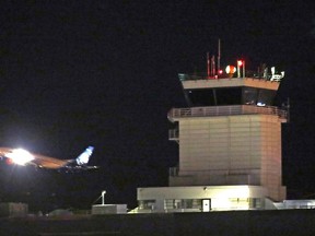 A plane flies past a control tower at Sea-Tac International Airport Friday evening, Aug. 10, 2018, in SeaTac, Wash. An airline mechanic stole an Alaska Airlines plane without any passengers and took off from Sea-Tac International Airport in Washington state on Friday night before crashing near Ketron Island, officials said.