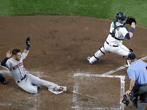 Houston Astros' Alex Bregman, left, scores as Seattle Mariners catcher Mike Zunino waits for the ball and umpire Mike Muchlinski looks on in the third inning of a baseball game Monday, Aug. 20, 2018, in Seattle.