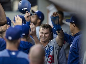 Los Angeles Dodgers' Joc Pederson is congratulated by teammates in the dugout after scoring against the Seattle Mariners during the first inning of a baseball game Saturday, Aug. 18, 2018, in Seattle.