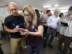 Dave Williams, left, and his daughter Cat Williams, second from left, look at early results in Washington state's primary election, Tuesday, Aug. 7, 2018, at a gathering at a combined campaign headquarters for Democrats running for office in Redmond, Wash.