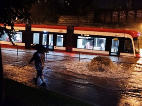 Water overflows from heavy rain, stopping a streetcar on King St. W. in Toronto on Tuesday, August 7, 2018.