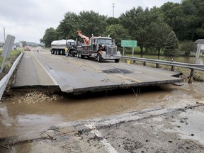 A milk truck was damaged early morning Tuesday, Aug. 21, 2018, when it fell into the missing section of a bridge over Highway 14 in Black Earth, Wis. More than 11 inches (28 centimeters) of rain fell overnight in places in or around Madison, according to the National Weather Service.