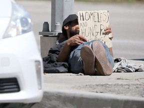 A man with a "homeless" sign on the side of the road in Winnipeg.
