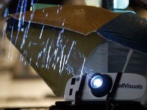 A projector is shielded from the rain as a message is projected on the Environmental Protection Agency, Monday, July 23, 2018, in Washington.  In a city with a long tradition of leftist street activism, Bell has become something of a local celebrity. Every few weeks, Bell puts messages of protest on the side of the Trump International Hotel. He's called President Donald Trump a pig and a racist, used smiling poop emojis, and taunted the president with images of his former lawyer, Michael Cohen.