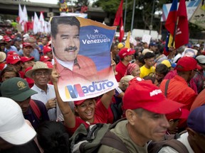 A supporter of Venezuela's President Nicolas Maduro holds up his picture during a rally in Caracas, Venezuela, Monday, Aug. 13, 2018. The United Socialist Party of Venezuela (PSUV) organized the rally to show support for the president following what the government called a failed assassination attempt with explosives-laden drones.