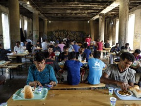 In this photo taken on Monday, Aug. 13, 2018, migrants eat lunch in a makeshift migrant camp in Bihac, 450 kms northwest of Sarajevo, Bosnia. Impoverished Bosnia must race against time to secure proper shelters for at least 4,000 migrants and refugees expected to be stranded in its territory during coming winter. The migrant trail shifted toward Bosnia as other migration routes to Western Europe from the Balkans were closed off over the past year.