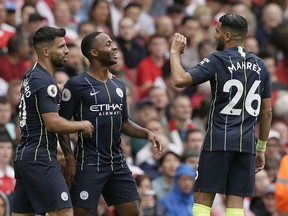 Manchester City's Raheem Sterling, center, celebrates with Sergio Aguero and Riyad Mahrez, right, after scoring the opening goal during the English Premier League soccer match between Arsenal and Manchester City at the Emirates stadium in London, England, Sunday, Aug. 12, 2018.