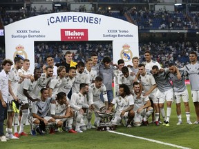 FILE - In this Saturday, Aug. 11, 2018 file photo, Real Madrid players pose with the trophy after winning the Santiago Bernabeu trophy soccer match between Real Madrid and AC Milan at the Santiago Bernabeu stadium, in Madrid. Real Madrid's rebuilding process after the departures of Cristiano Ronaldo and Zinedine Zidane gets its first test against crosstown rival Atletico Madrid in the UEFA Super Cup in Estonia on Wednesday, Aug. 15, 2018.