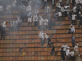 Brazil's Santos soccer fans throw seats and light flares from the grand stand after their team lost, on aggregate, a Copa Libertadores soccer match to Argentina's Independiente, in Sao Paulo, Brazil, Tuesday, Aug. 28, 2018. Independent won 3-0 on aggregate.