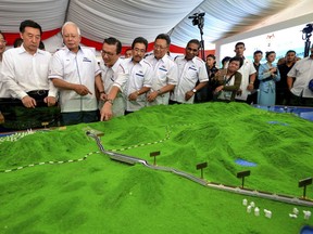 FILE - In this Sept. 8, 2017, file photo, Malaysia former Prime Minster Najib Razak, third from left, looks at modals of ECRL (East Coast Rail Link) during the project launching in Kuantan, east cost of peninsula Malaysia. Malaysia's state news agency has cited Prime Minister Mahathir Mohammad as saying that multibillion-dollar China-financed projects have been canceled. Bernama says Mahathir told Malaysian reporters during the final day of a visit to Beijing on Tuesday, Aug. 21, 2018 that both Chinese President Xi Jinping and Premier Li Keqiang understood the reasons behind the cancellations and "accepted them." (AP Photo, File)