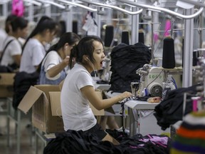 In this Thursday, Aug. 2, 2018, photo, a woman yawns at a factory making swimming suits in Jinjiang city in southeast China's Fujian province. China's exports accelerated in July, showing little impact from a U.S. tariff hike, while sales to the United States rose 13.3 percent over a year earlier. (Chinatopix via AP)