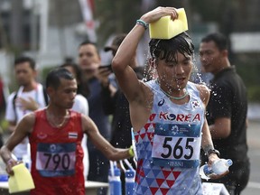 South Korea's Kim Jae-hoon cools himself down with wet sponge during the men's marathon at the 18th Asian Games in Jakarta, Indonesia, Saturday, Aug. 25, 2018.