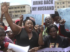 FILE - In this Wednesday, March, 9, 2016 file photo Sheffra Dzamara, right, wife to abducted activist Itai Dzamara, holds a placard calling for his return during a demonstration to commemorate a year since his disappearance. Amnesty International's new leader, Kumi Naidoo, says his first act is writing to Zimbabwe's next president about the disappearance of Dzamara, saying "whoever leads the new government must move to undo the injustices of the past." Kumi Naidoo's focus on Dzamara, who disappeared in 2015 under Zimbabwe's former leader Robert Mugabe, puts further pressure on President-elect Emmerson Mnangagwa's government to acknowledge past abuses.