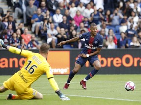 Angers goalkeeper Ludovic Butelle, left, makes a save in front of PSG's Kylian Mbappe during the French League One soccer match between Paris Saint Germain and Angers at the Parc des Princes stadium in Paris, Saturday, Aug. 25, 2018.