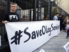 People hold posters to support Ukrainian filmmaker Oleg Sentsov, who is currently on hunger strike in a Russian jail to demand the release of the other Ukrainian hostages taken by the Kremlin, in front of the Embassy of the Russian Federation in Kiev, Ukraine, Tuesday, Aug. 21, 2018. Today is the 100th day since the beginning of the indefinite hunger strike of Oleg Sentsov, announced on May 14, 2018, demanding the release of all Ukrainian political prisoners of the Kremlin.