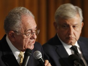 Mexico's President Elect Andres Manuel Lopez Obrador, right, listens to his Secretary of Communication and Transport Javier Jimenez Espriu during a press conference about the the future of Mexico City's planned new airport, in Mexico City, Friday, Aug. 17, 2018.