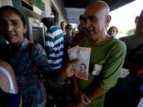 A woman shows a couple of new five "sovereign bolivar" Venezuelan bank notes, released from a government bank in Maracaibo, Venezuela, Tuesday, Aug. 21, 2018. The new currency will have two coins and paper denominations ranging from 2 up to 500. The lowest represents the buying power of 200,000 current bolivars while the highest stands in for 50 million.