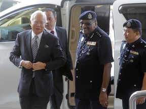 Malaysian former Prime Minister Najib Razak, left, arrives at High Court of Malaya in Kuala Lumpur, Malaysia, Friday, Aug. 10, 2018. Najib was charged of money laundering on Wednesday over a multibillion-dollar graft scandal at a state investment fund, the anti-corruption agency said.