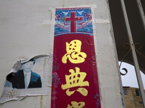 In this photo taken Friday, June 1, 2018, a faded photo of Chinese President Xi Jinping is seen near the Christian poster with the word "Grace" outside a house church near Nanyang in central China's Henan province. Under President Xi Jinping, China's most powerful leader since Mao Zedong, believers are seeing their freedoms shrink dramatically even as the country undergoes a religious revival. Experts and activists say that as he consolidates his power, Xi is waging the most severe systematic suppression of Christianity in the country since religious freedom was written into the Chinese constitution in 1982.