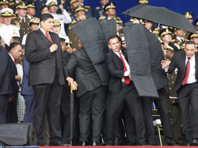 In this photo released by China's Xinhua News Agency, security personnel surround Venezuela's President Nicolas Maduro during an incident as he was giving a speech in Caracas, Venezuela, Saturday, Aug. 4, 2018. Drones armed with explosives detonated near Venezuelan President Nicolas Maduro as he gave a speech to hundreds of soldiers in Caracas on Saturday but the socialist leader was unharmed, according to the government.