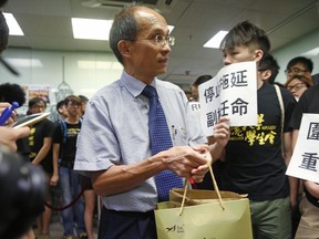 In this July 28, 2015 photo, University of Hong Kong Professor, Cheung Kie-chung, center, attends a conference in Hong Kong.  Media reports say the Hong Kong university professor has been arrested after his wife's decomposing body was found inside a suitcase in his campus office.  The Wednesday, Aug. 29, 2018,  reports said Hong Kong University mechanical engineering associate professor Cheung was taken away by police on Tuesday, Aug. 28. (Apple Daily via AP)