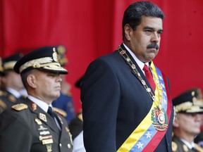 FILE - In this  May 24, 2018 file photo, Venezuela's President Nicolas Maduro watches a military parade, alongside his Defense Minister Vladimir Padrino Lopez, behind, at Fort Tiuna in Caracas, Venezuela. State television in Venezuela showed President Maduro abruptly cutting short a speech on Saturday, Aug. 4, causing hundreds of soldiers present to break ranks and scatter.