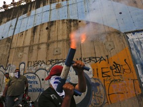 FILE - In this July 26, 2018 file photo, a demonstrator fires a home made mortar while others gather to commemorate 100 days of anti-government protests demanding the resignation of President Daniel Ortega and the release of all political prisoners, in Managua, Nicaragua. The rights group, Nicaraguan Pro-Human Rights Association, which has documented killings during months of political unrest, says it is closing its offices due to threats and harassment.