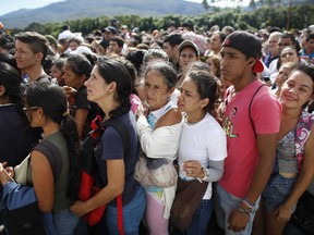 FILE - In this July 17, 2016 file photo, Venezuelans wait in line to cross into Colombia through the Simon Bolivar bridge in San Antonio del Tachira, Venezuela. The United Nations says an estimated 2.3 million Venezuelans had fled the country as of June 2018, mainly to Colombia, Ecuador, Peru and Brazil.