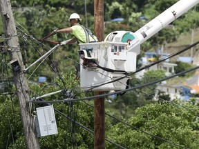 FILE- In this May 16, 2018 file photo, a worker from the Cobra Energy Company, contracted by the Army Corps of Engineers, installs power lines in the Barrio Martorel area of Yabucoa, Puerto Rico. Officials said on Tuesday, Aug. 14, that the power has been restored to the entire island for the first time since Hurricane Maria struck nearly 11 months ago.