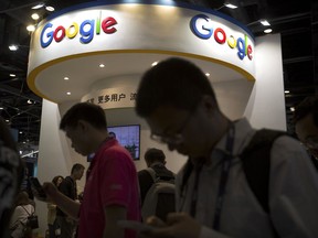 FILE - In this April 27, 2017, file photo, visitors use their smartphones in front of a booth for Google at the Global Mobile Internet Conference (GMIC) in Beijing. More than a dozen human rights groups have sent a letter dated Tuesday, Aug. 28, 2018, to Google urging the company not to offer censored internet search in China, amid reports it is planning to again begin offering the service in the giant Asian market.