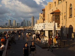 In this Saturday, July 28, 2018 photo, people enjoy the day on Jaffa's promenade overlooking Tel Aviv's skyline and the Mediterranean sea in Jaffa, Israel. Israel's port city of Jaffa is an ancient place. Today glass towers and modern apartment complexes rise amid Jaffa's old white stone buildings. It's famous for its flea market and hummus cafes. But visitors will also find trendy bars, galleries and boutiques.