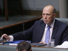 Australian former Home Affairs Minister Peter Dutton sits in the back left seat in Parliament in Canberra, Australia, Wednesday, Aug. 22, 2018. Dutton moved from the front row where Cabinet ministers sit to the back row after his bid to become prime minister failed on Tuesday.