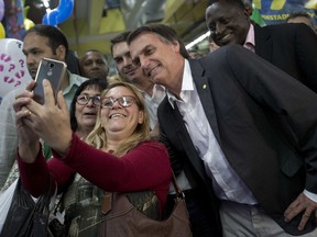 Women take a selfie with National Social Liberal Party presidential candidate Jair Bolsonaro as he campaigns at the Madureira market in Rio de Janeiro, Brazil, Monday, Aug. 27, 2018. Brazil will hold general elections on Oct. 7.