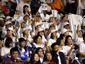 Supporters wave flags as they watch the women's basketball match between the combined Koreas and Indonesia at the 18th Asian Games in Jakarta, Indonesia, Wednesday, Aug. 15, 2018.
