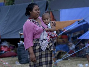 A woman carries her child at a temporary shelter after being displaced by Sunday's earthquake in North Lombok, Indonesia, Wednesday, Aug. 8, 2018.