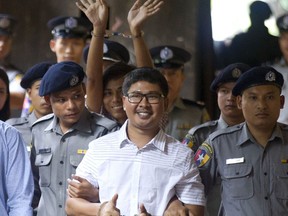 Two Reuters journalists Wa Lone, center, and Kyaw Soe Oo, center back, gestures while being escorted by police upon arrival at a court Monday, Aug. 27, 2018, in Yangon, Myanmar. The Myanmar court delayed the verdict against two Reuters journalists on the charge of possessing official documents illegally in a case that has drawn attention to the faltering state of press freedom in the troubled Southeast Asian nation. The verdict that was to be delivered Monday was postponed to Sept. 3.