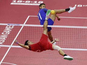 Lao's Noum Souvannalith, left, kicks a ball against Thailand's Jirasak Pakbuangoen during the men's sepak takraw team doubles final match at the 18th Asian Games in Palembang, Indonesia, Saturday, Aug. 25, 2018.