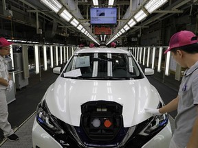 Chinese workers inspect a Nissan Sylphy Zero Emission, Nissan's first all-electric vehicle built in China, at a production line in Guangzhou, Guangdong province, China, Monday, Aug. 27, 2018. The Sylphy is part of a wave of dozens of electric models planned by global automakers for China, where the government is pressing them to accelerate development of the technology.