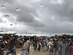 In this Tuesday, June 26, 2018, photo, Rohingya refugees walk on a muddy road in the rain through Jamtoli refugee camp in Bangladesh. For the hundreds of thousands of Rohingya children living in Bangladesh's refugee camps, dangers lurk everywhere: from malnutrition and disease to human traffickers to flooding and landslides.