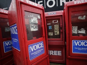 Newspaper boxes for The Village Voice stand along a Manhattan sidewalk in New York.