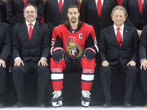 In this March 7 file photo, Ottawa Senators GM Pierre Dorion (left), captain Erik Karlsson (centre) and owner Eugene Melnyk pose for the team's annual group photo at the Canadian Tire Centre.