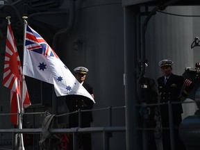 Japanese naval officers are seen before welcoming the media on a tour of the Japanese Asagiri-class destroyer, JDS Umigiri docked in Sydney's Naval base on April 19, 2016.