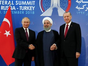 A handout picture taken and released on September 7, 2018 by the Turkish Presidential Press service shows Turkish President Recep Tayyip Erdogan (R), Iranian President Hassan Rouhani (C) and Russian President Vladimir Putin (L) joining hands during a trilateral summit in Tehran.